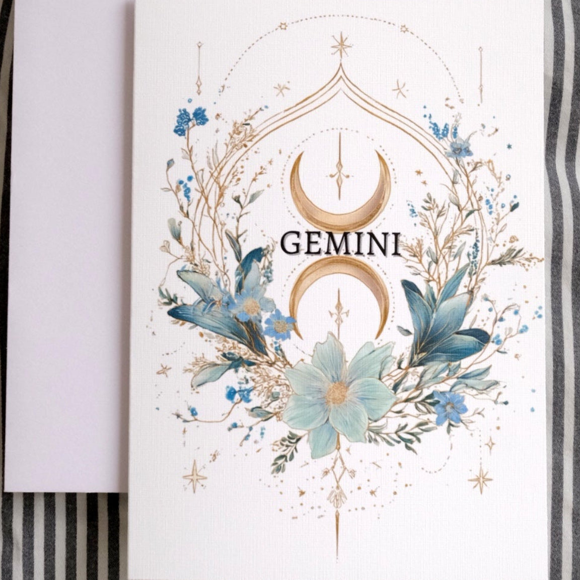 Card with 'Gemini' design featuring floral elements on a striped fabric background