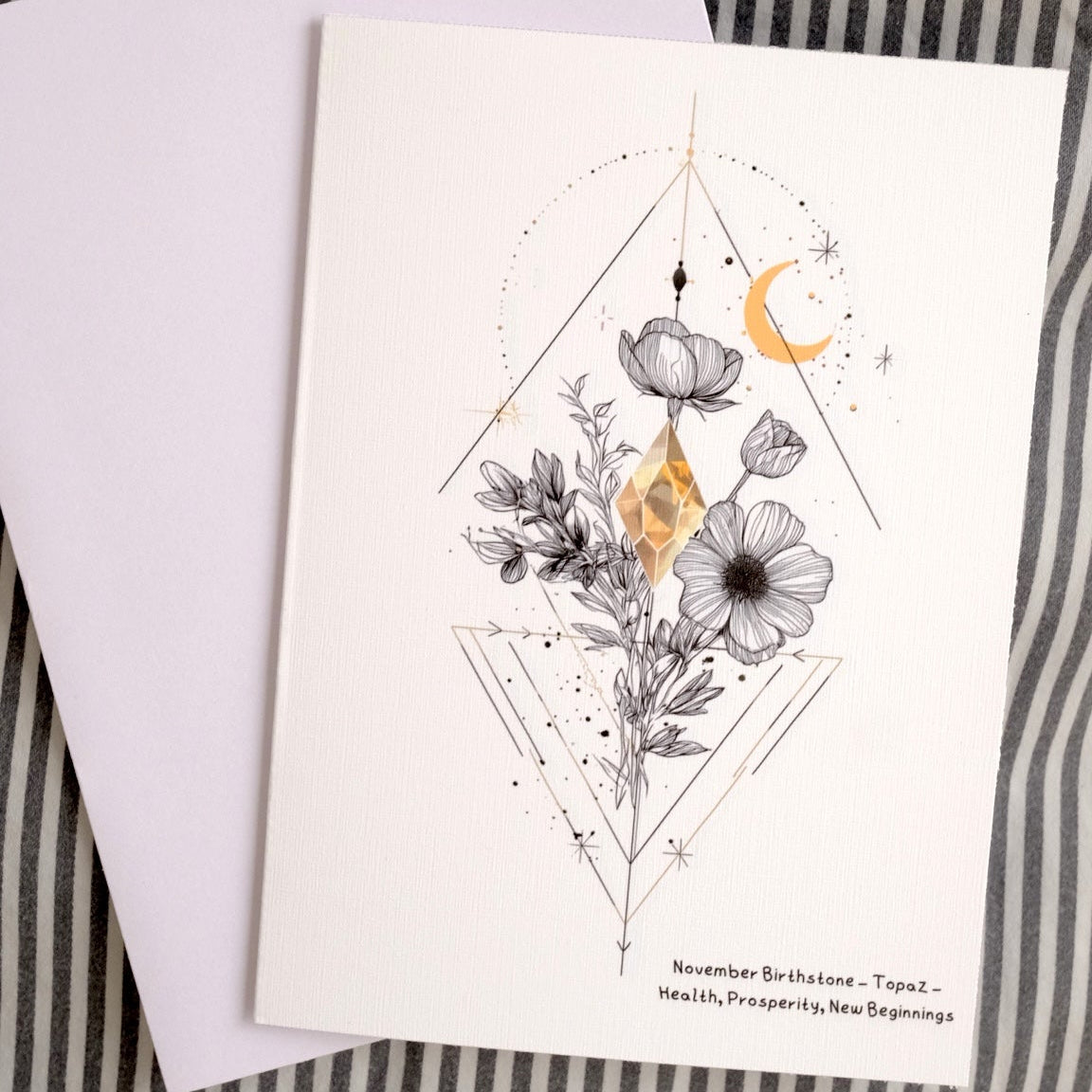 Greeting card with floral and moon design on a striped fabric background